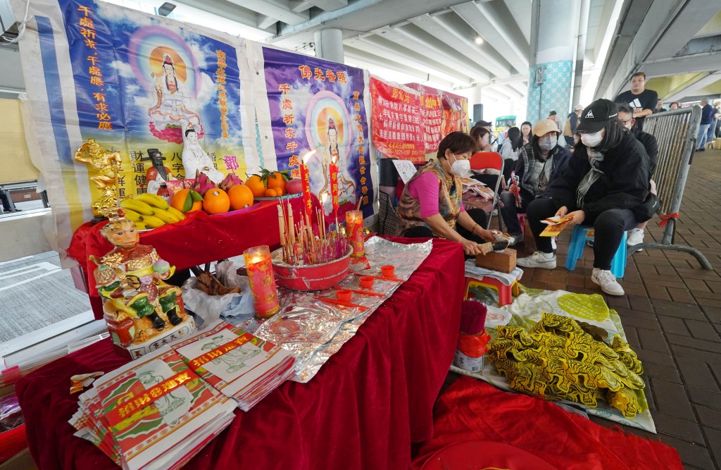 神婆攤檔前擺滿祭祀用的衣紙和供品。 神婆攤檔前擺滿祭祀用的衣紙和供品。