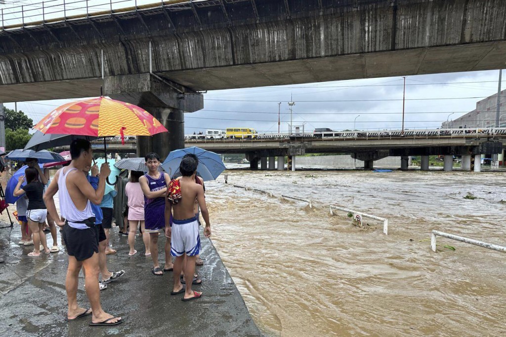 居民看着马里基纳河因近台风格美加剧降雨而泛滥。 美联社