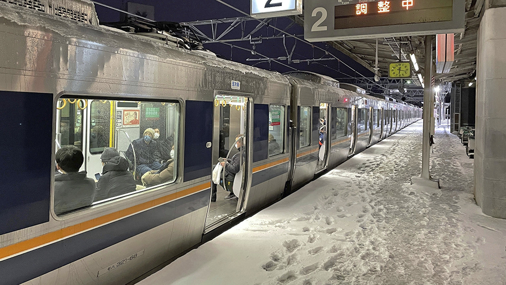 日本京都受到大雪影響，鐵路列車25日停靠在西大路站暫停行駛。AP