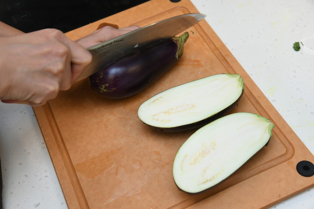 Step 2: 茄子去蒂及对切，在表面轻轻划出格子状。 Remove the stems and cut the eggplant into halves, and lightly make grids on the surface.