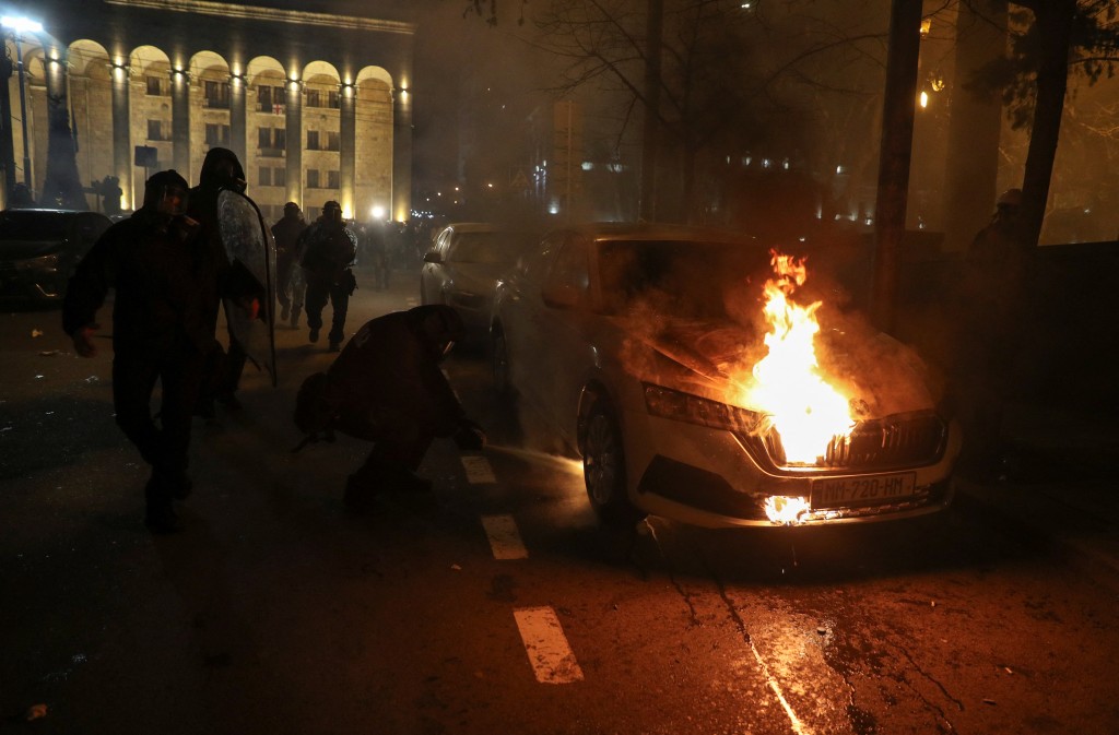格魯吉亞大規模示威反對外國代理人法案，執法人員試圖靠近一輛被縱火的車滅火。 路透社