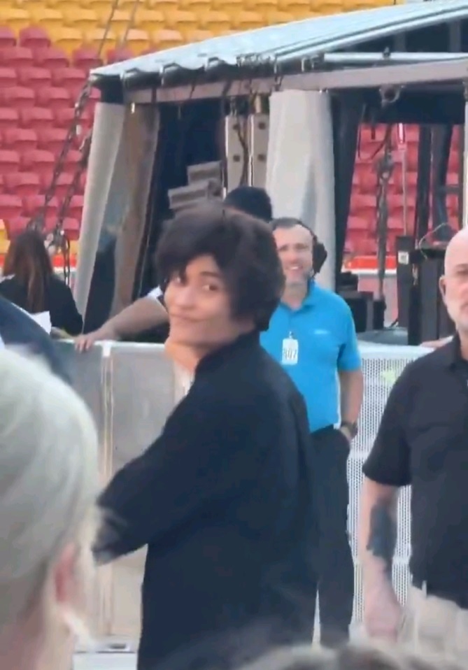 旁邊群眾認出他後紛紛叫嚷着「趕他走」，他卻轉過頭來向群眾詭異地微笑。（粉絲片段截圖）