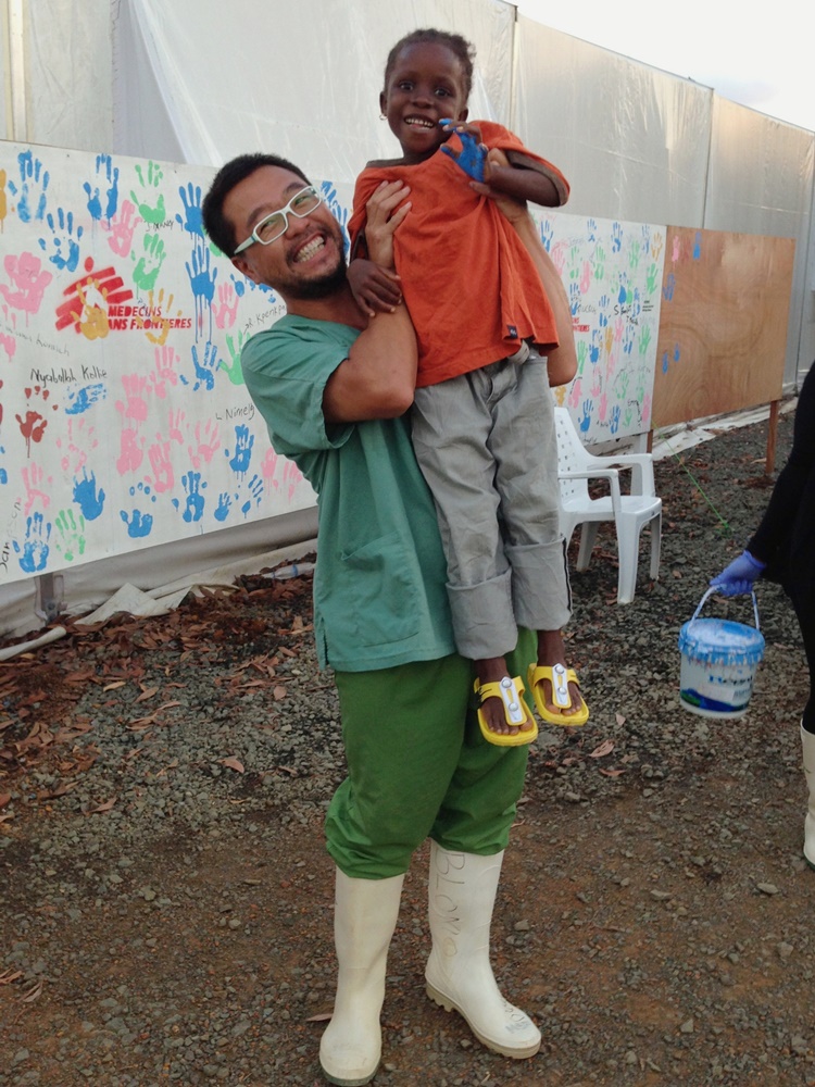 在港任職急症室護士的趙卓邦，於2014年前往利比里亞參與應對當時的伊波拉疫情。一名男孩痊瘉出院時與趙卓邦合照，並和其他康復者一樣在治療中心外的牆上印上手掌印，加強當地人對克服疫症的信心。© MSF