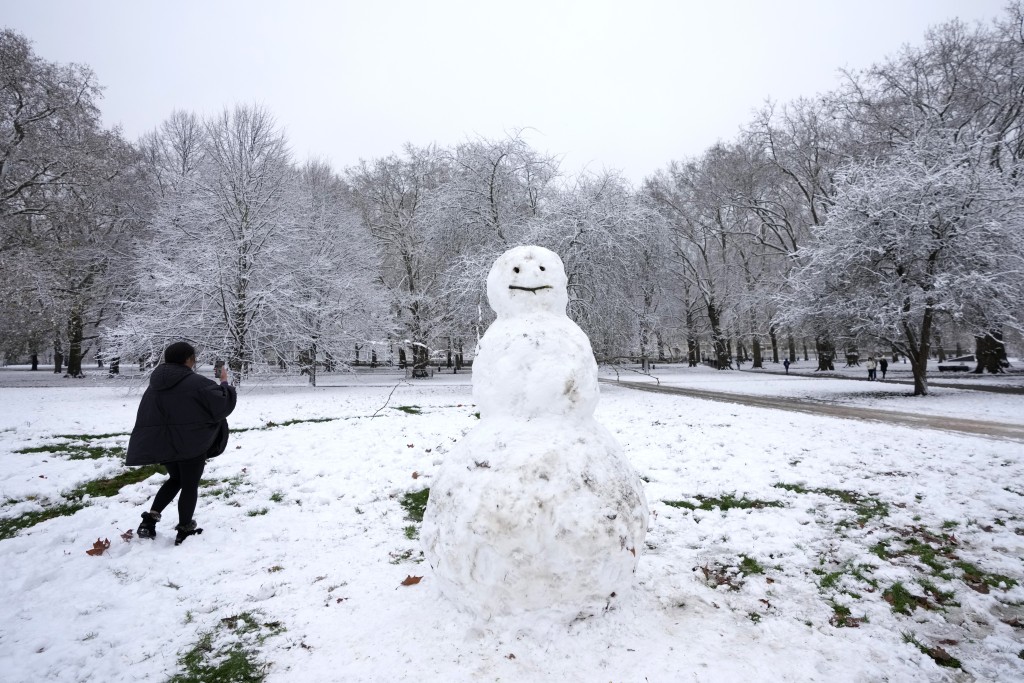 一名妇女在伦敦格林公园拍摄雪人。AP