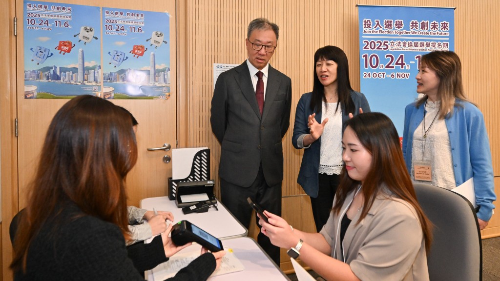 陸啟康(後排左)在選舉事務處總選舉事務主任陳淑華(後排中)陪同下,了解繳交選舉按金的安排。 陸啟康(後排左)在選舉事務處總選舉事務主任陳淑華(後排中)陪同下,了解繳交選舉按金的安排。