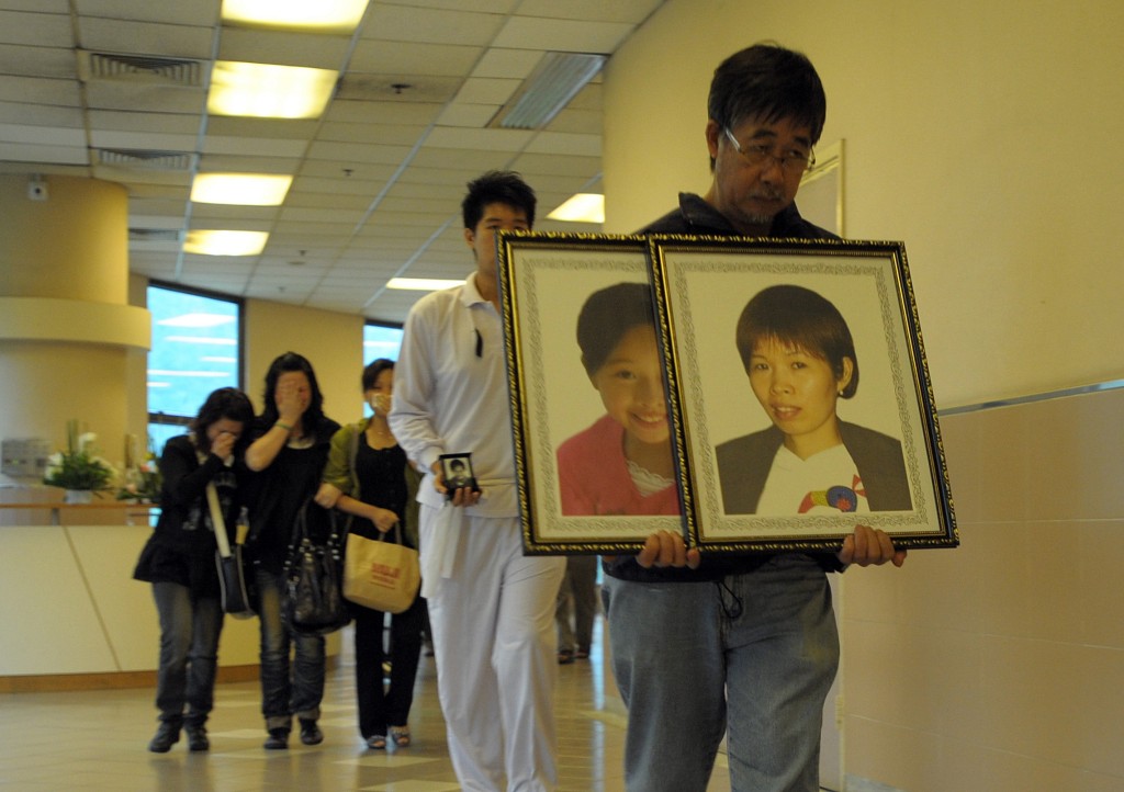 簡福駒掛住兩死者遺照上山。資料圖片