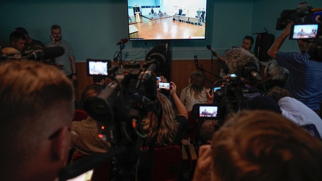 記者圍觀俄羅斯當局提供的納瓦爾尼受審法庭轉播畫面。 美聯社