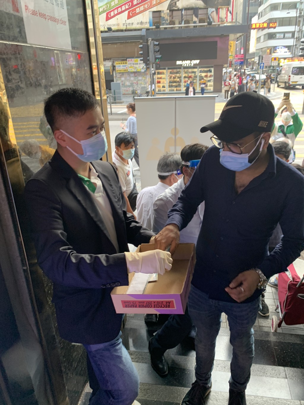 油尖旺民政事务专员余健强（左）三月五日向重庆大厦的居民派发快速测试套装。