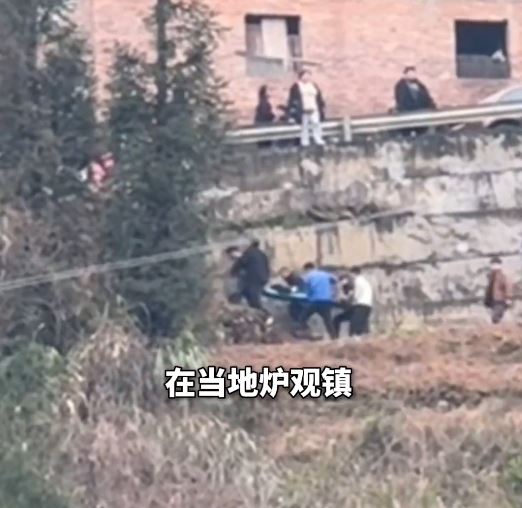 救援人員用擔架將墜崖消防員抬走。極目新聞