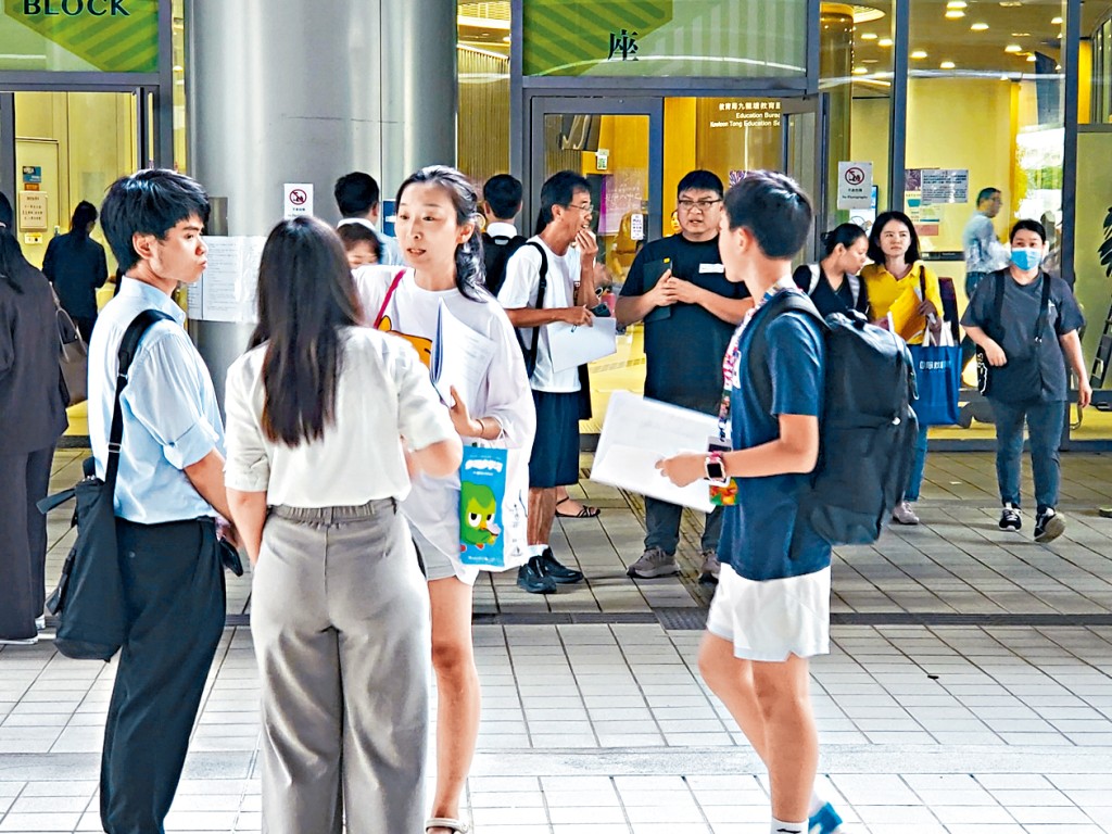 在九龍塘教育局學位分配組辦公室外,不少教師向剛領取派位證的家長推銷自己的學校。