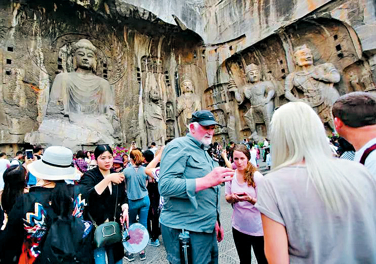 外國旅客遊覽河南洛陽龍門石窟。