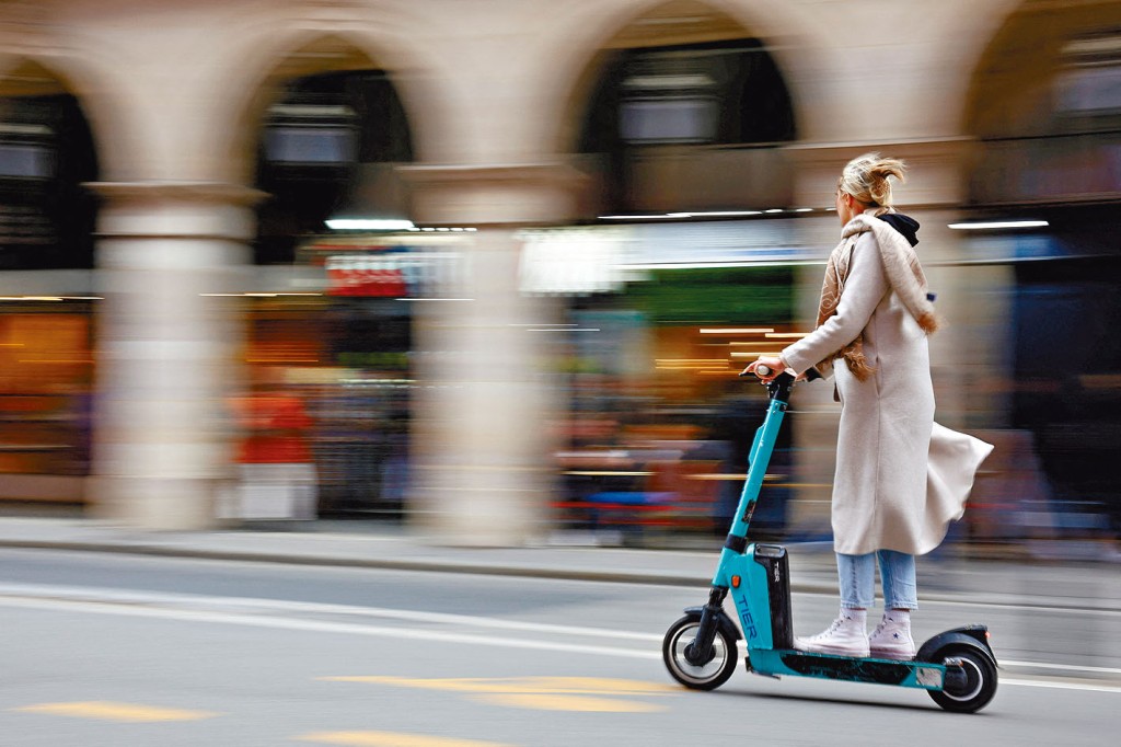 在巴黎街頭使用Tier電動滑板車的女子。