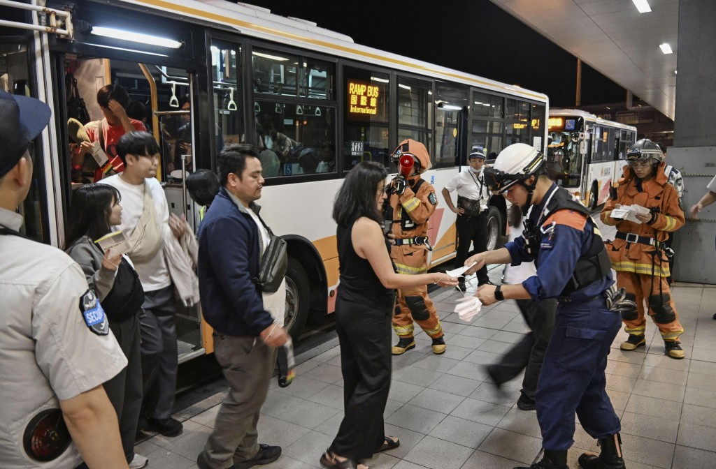 乘客自逃生滑梯疏散後，轉乘巴士抵達關西機場客運大樓。路透社
