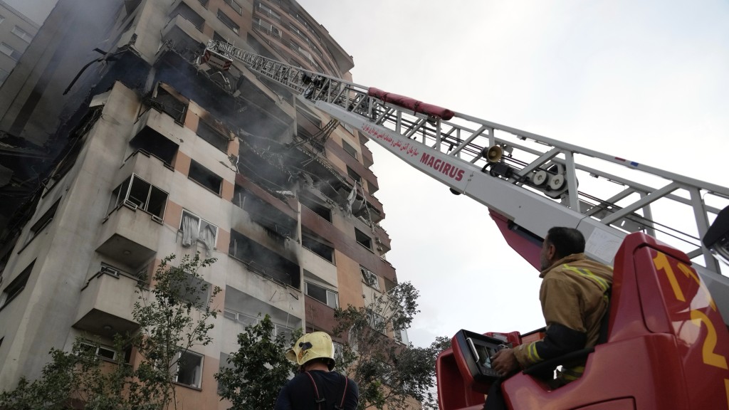 德黑蘭北部一座住宅大樓被擊中,消防出動雲梯。 美聯社 德黑蘭北部一座住宅大樓被擊中,消防出動雲梯。 美聯社