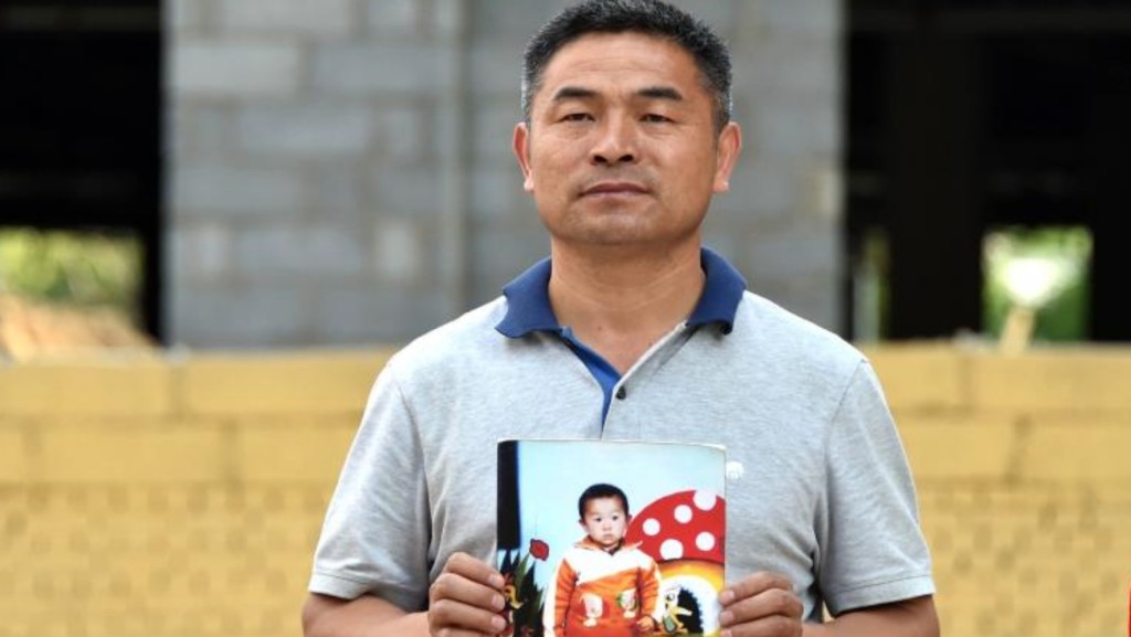 2015年郭剛堂展示郭新振被拐前的照片。新華社