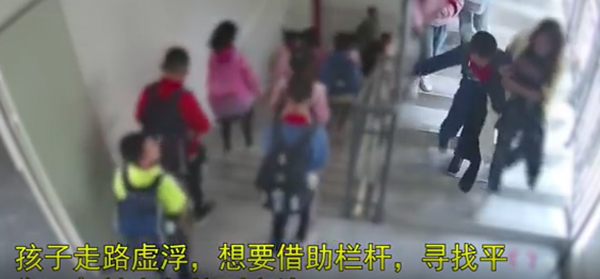 男童由老师搀扶走下楼梯时，之后摔倒。网片截图