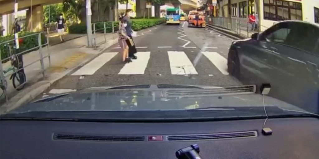 該對母女亦嚇得立即停下，等待私家車橫過後始續過馬路。 影片截圖