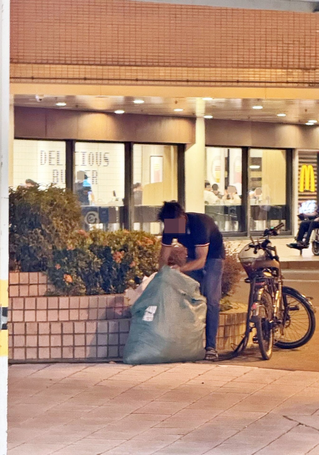 相信是涉事的男子在天瑞 商場一快餐店對出，埋首整理麻包袋內 滿載的疑似布料物品。Threads截圖
