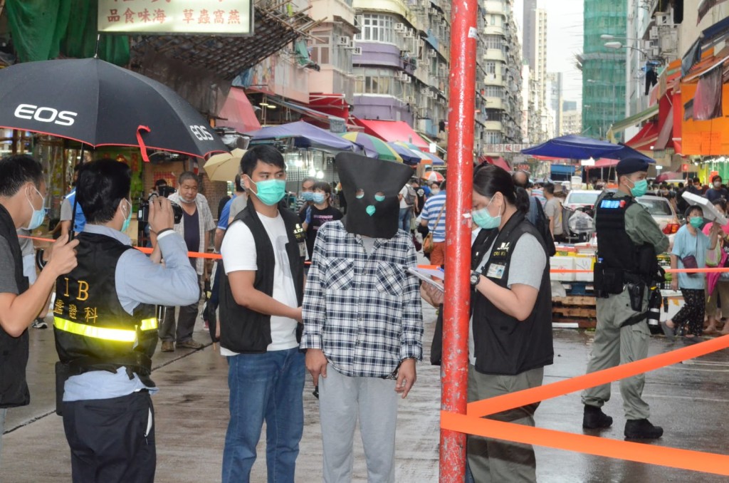 警方押解其中一名疑犯到涉事地點重組案情。