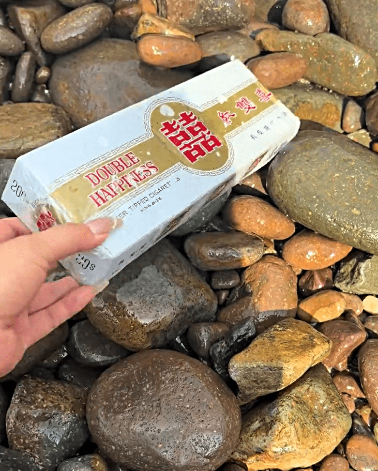 西貢破邊洲岸邊出現大批紅雙囍香煙。網片截圖
