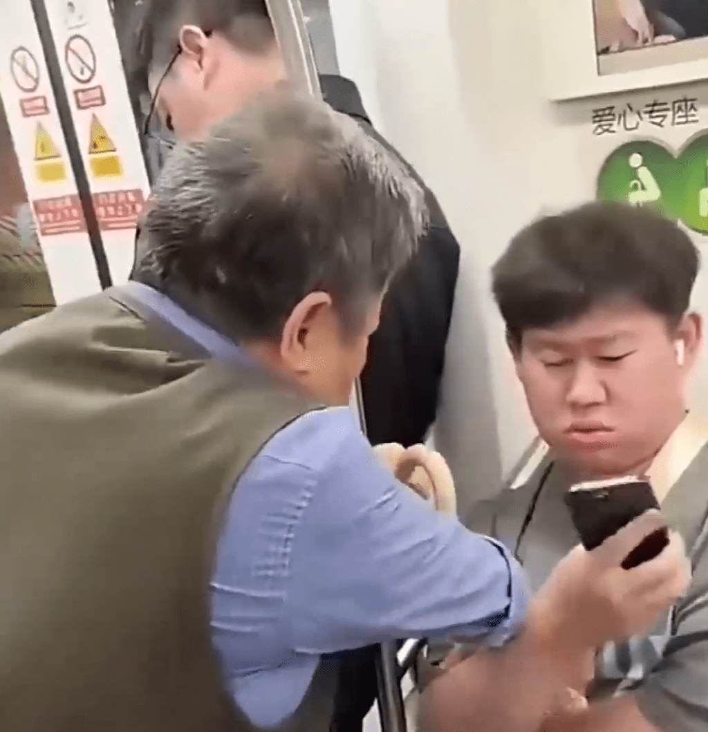 老翁糾纏身前的男乘客,要求讓座。 老翁糾纏身前的男乘客,要求讓座。