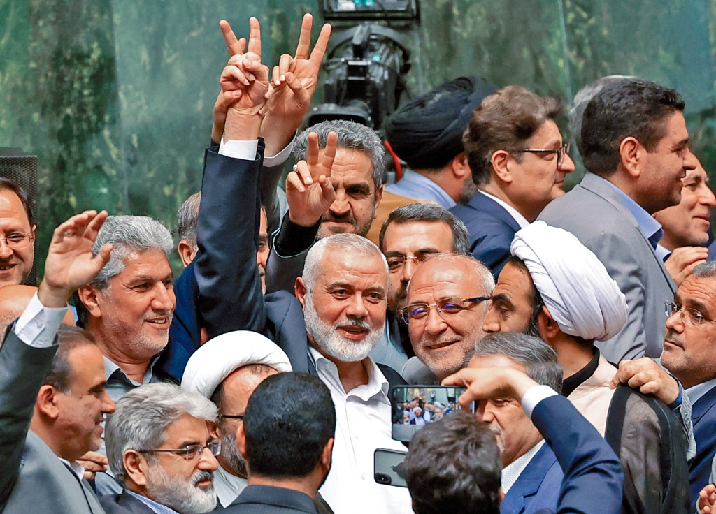 遇刺的哈馬斯政治領袖哈尼亞（中）周二到伊朗國會出席新總統宣誓就職儀式，在議員簇擁下打出勝利手勢。