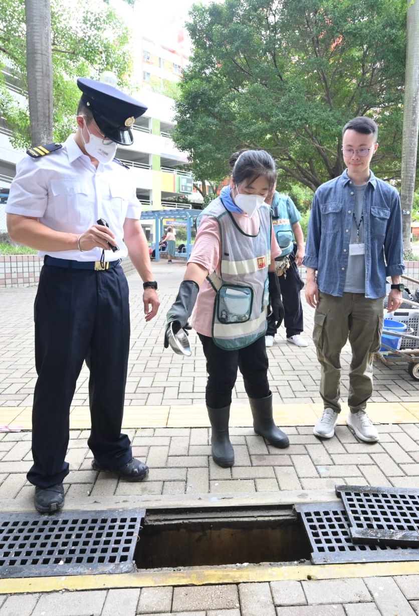 食環署人員指導房屋署外判清潔公司工人施放蚊沙。