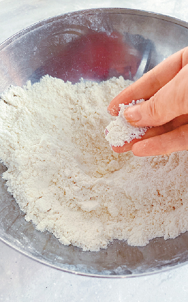 麵粉過篩，再注入糖、鹽和梳打粉（按口味加入材料B），拌勻。然後加入凍牛油粒，再用手將牛油捽入麵粉，直至呈麵包糠狀。