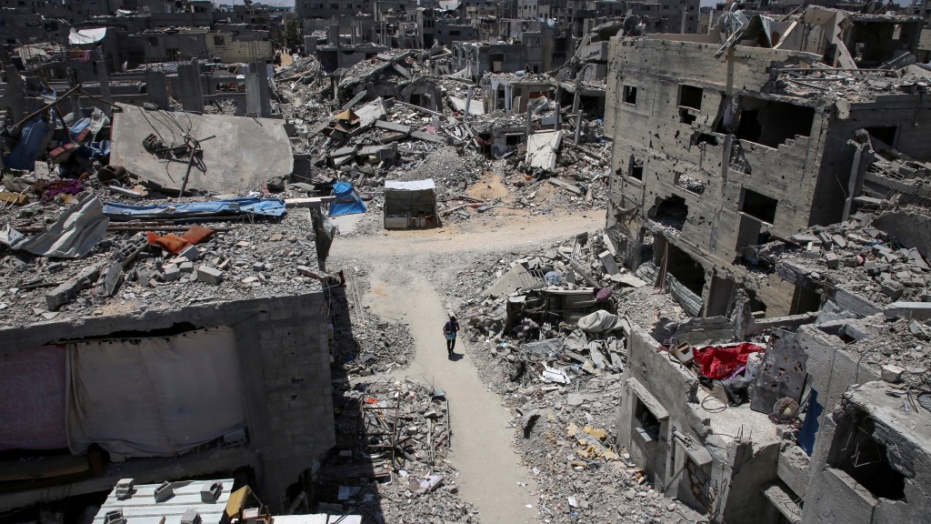 一名巴勒斯坦男子孩独地走在被炸毁的社区路上。 路透社