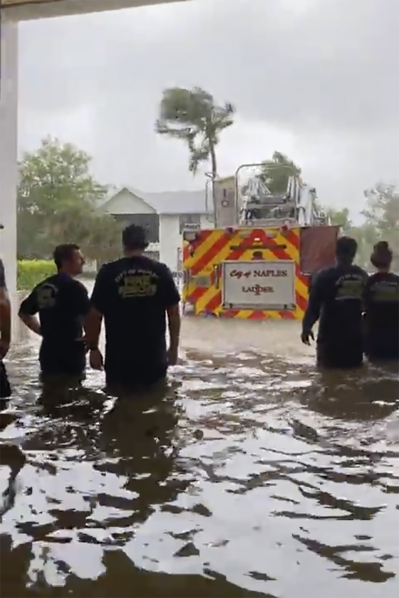 消防員看著因颶風伊恩引發的風暴潮而停在水中的救火車。AP