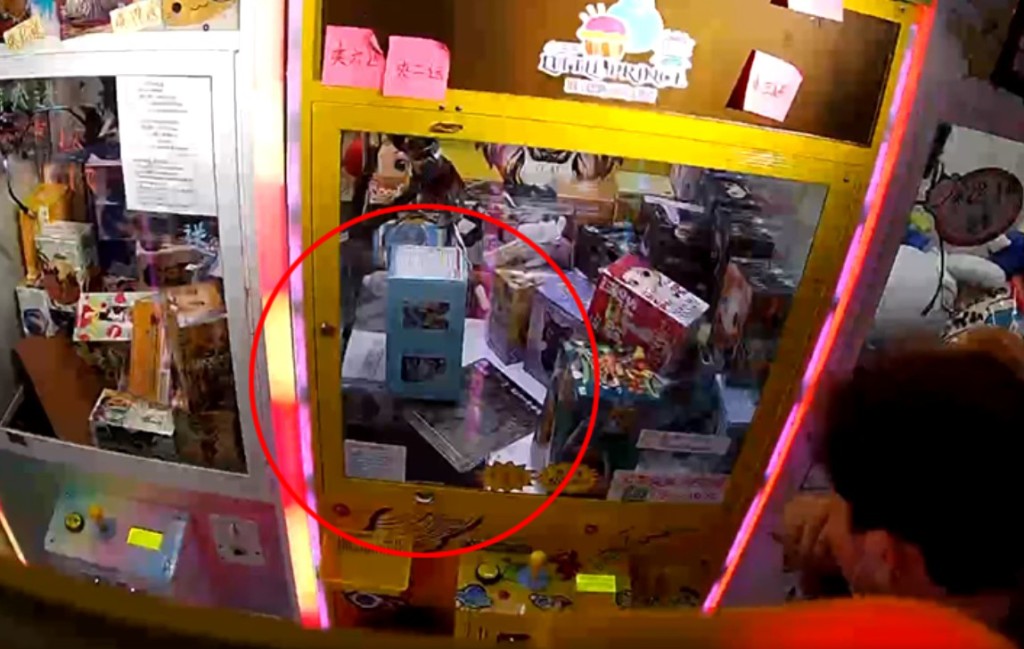 影片清晰看到当灰衣少年似爬入夹公仔机时，一只手伸进夹公仔机内，并取走一盒玩具。