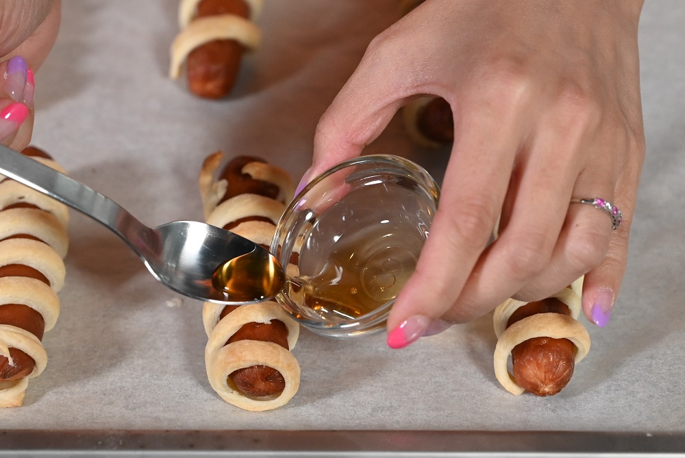 8. 用汤匙在眼球糖点上蜜糖。 Using a teaspoon , put a dot of honey on the sausages. 