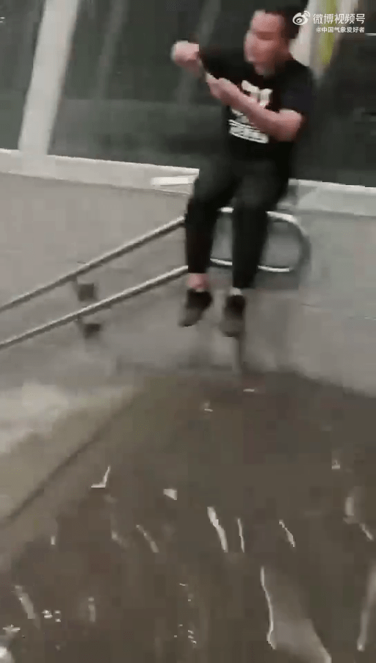 有乘客被困，坐在地鐵出口的扶手上拍攝水浸的情況。