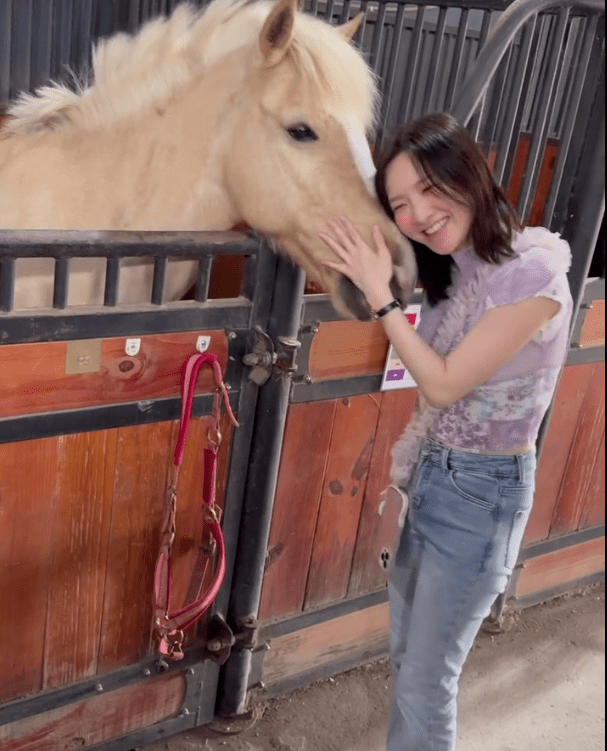 林欣彤與馬匹溫馨互動，展現燦爛笑容。