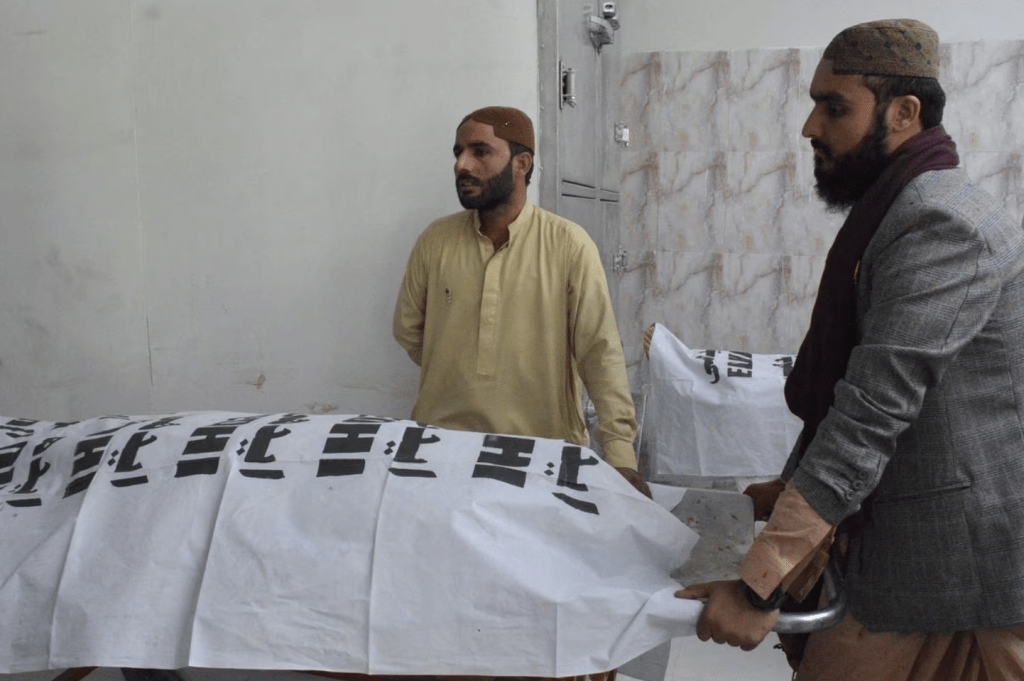 2023 年 9 月 29 日，巴基斯坦奎达医院，男子站在被遮盖的受害者尸体旁。路透社