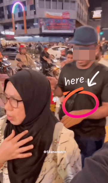 從影片可見，一名身穿黑衣、手持紙袋的男子緊貼在女事主身後。