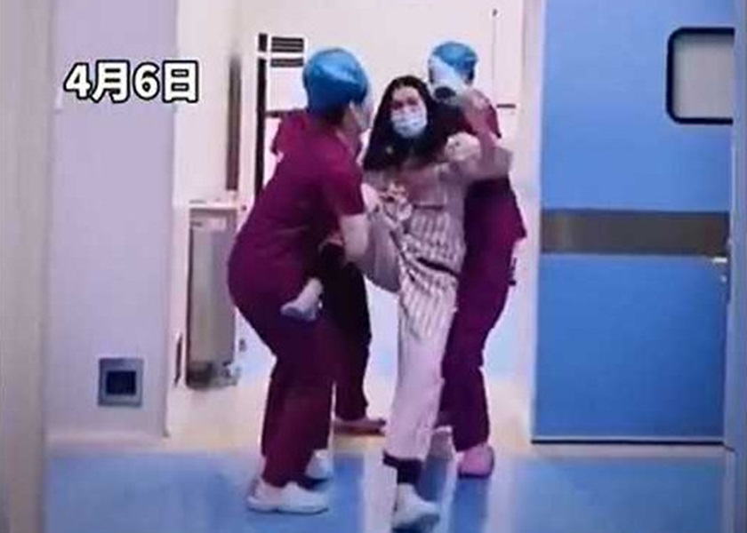 多名護士捉住婦人,阻止她動手。影片截圖