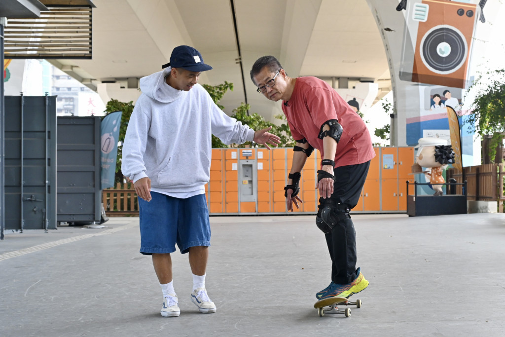 陳茂波向滑板精英運動員陸俊彥，以及幾位小運動員學習踩滑板。（陳茂波網誌圖片）