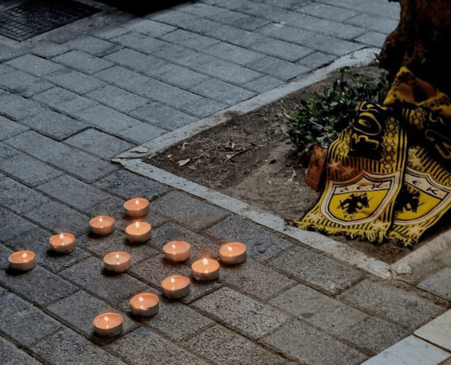 雅典球迷在死者麦克被刺的地方放上球队围巾，并将蜡烛排成代表麦克的Ｍ字。网上图片