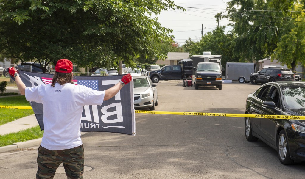 在犹他州普罗沃的一处住宅进行调查时，一名男子举著旗帜。AP