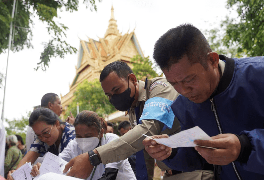 2023 年 7 月 23 日，柬埔寨金邊，人們在柬埔寨大選當天查看選民名單。路透社
