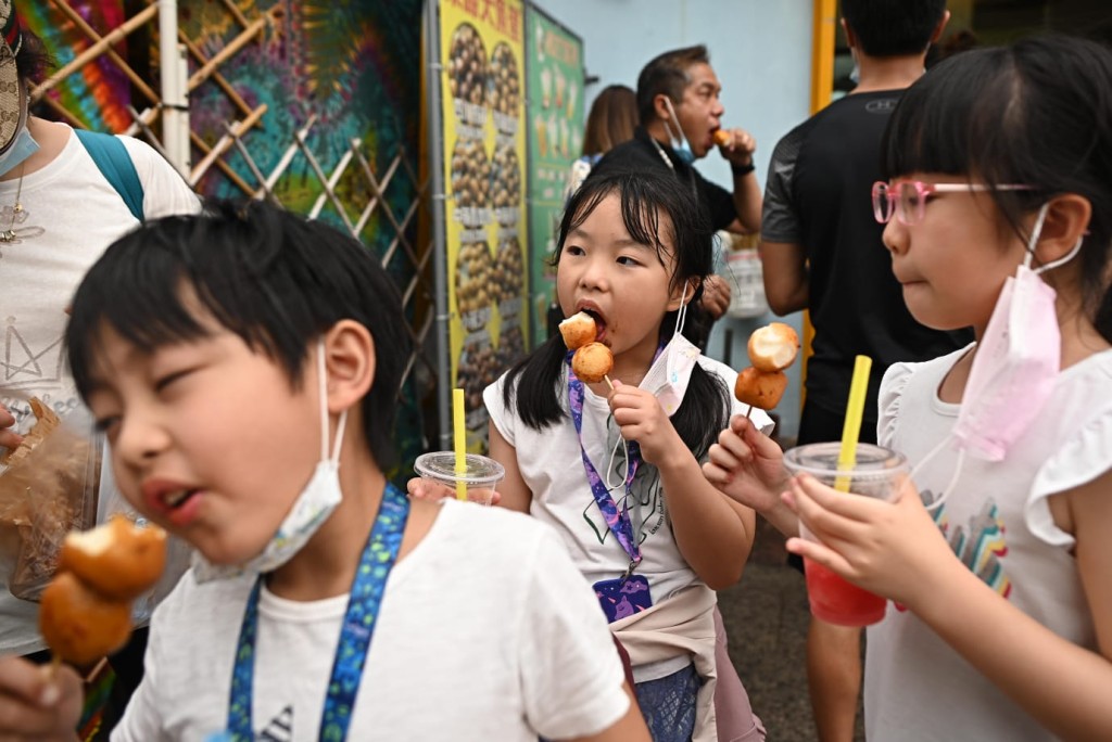 小朋友拉低口罩試吃特色小食大魚蛋。李睿哲攝