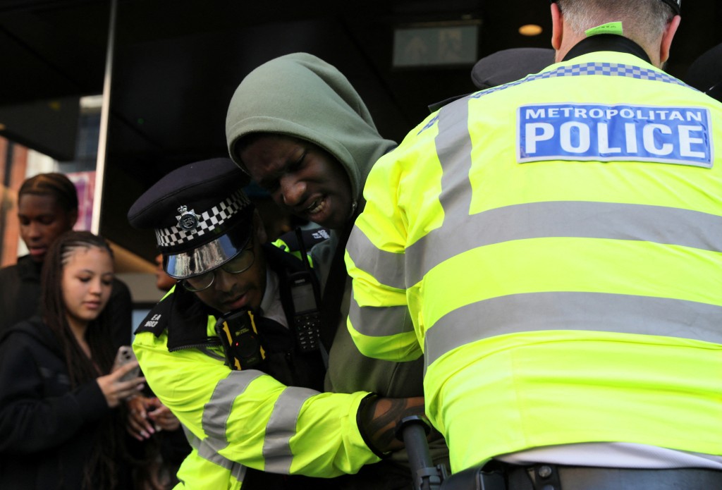 倫敦警察和搶店青年在街頭混戰。　路透社