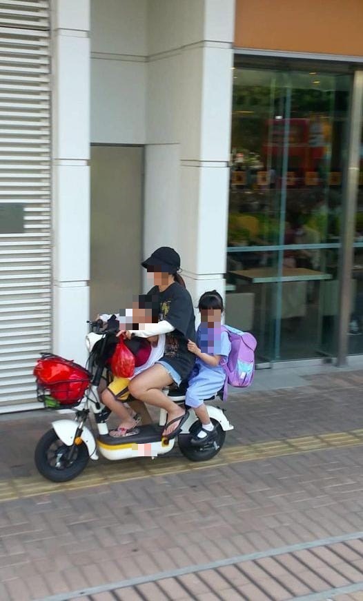 車上女子及所載兩兒童，均未戴頭盔，險象環生。網上圖片