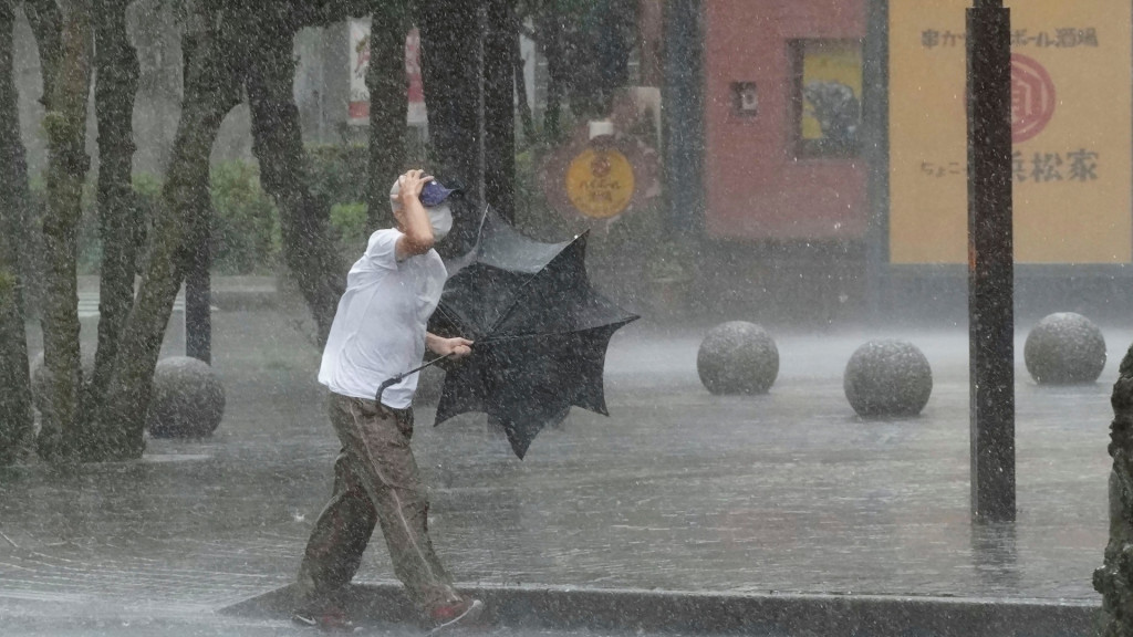 靜岡縣一名男子在大風大雨中前行。AP
