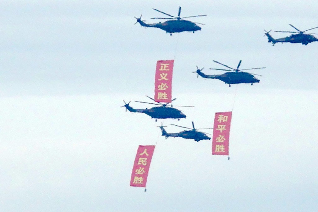 直升機拉起寫有「和平必勝」、「正義必勝」、「人民必勝」的直幡。路透社