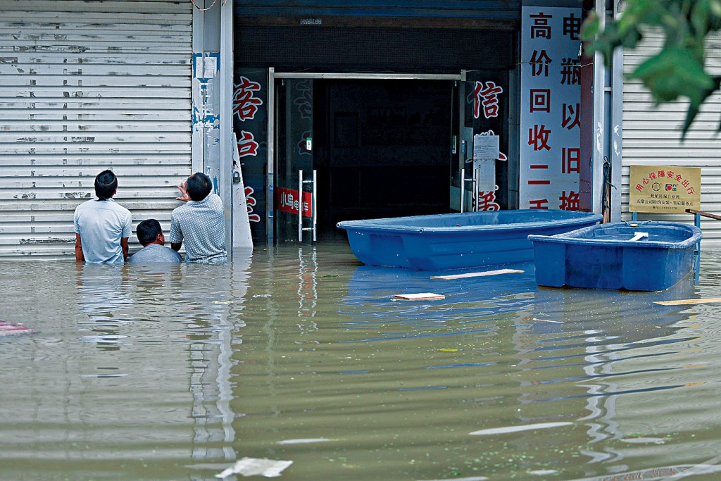 ■安徽巢湖柘皋鎮，民眾查看被水淹的店鋪情況。