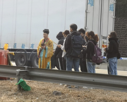 其中一名死者的家屬，帶同道士到車禍現場拜祭。