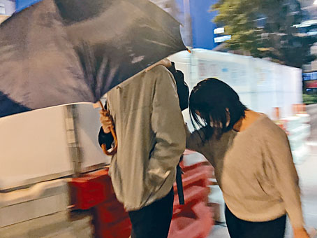 被告鄭偉森由他人陪同離開法庭時用傘遮面。