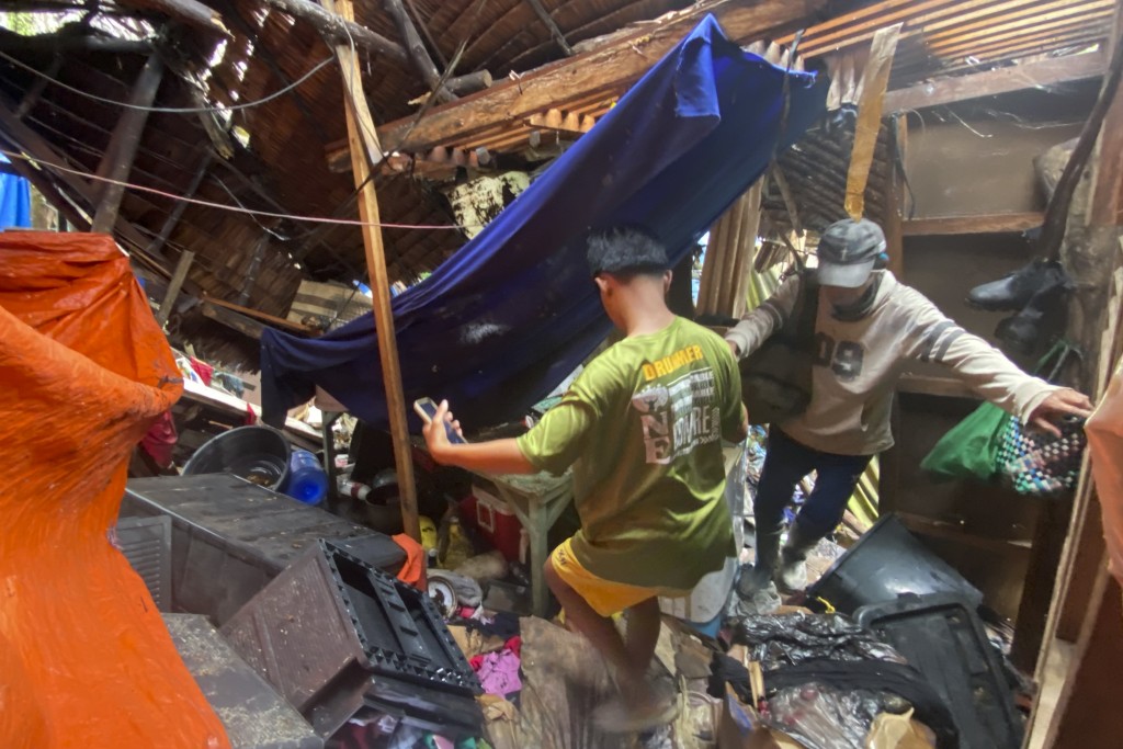 菲律宾南部苏里高省希纳图安镇的居民在撤离到安全地带时走过因地震被毁的房屋。 AP
